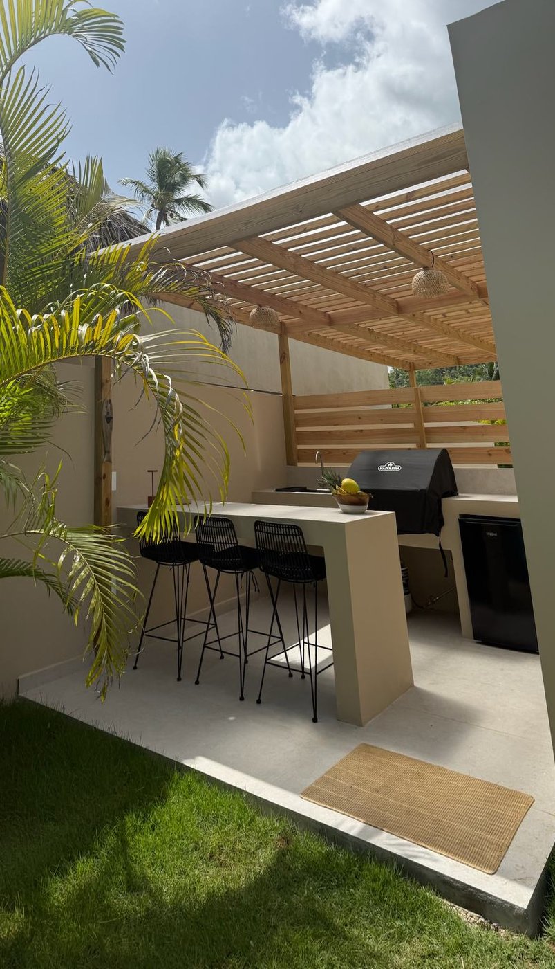 La cuisine d'été sous la pergola : bar, barbecue et frigo, ouverte sur le jardin — Villas Origen