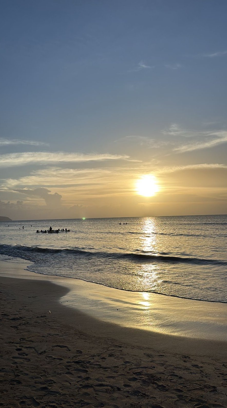 Coucher de soleil sur Playa Cosón, la mer calme et les baigneurs dans la lumière dorée