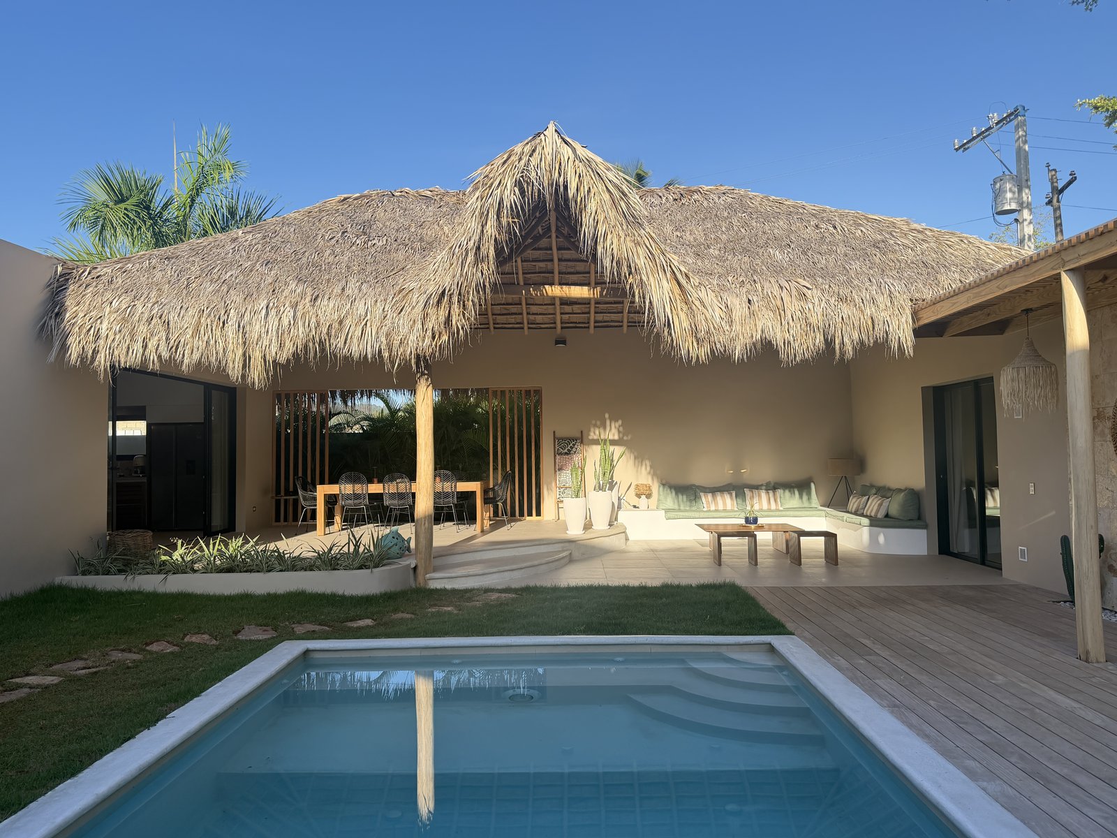 Le grand bohío au toit de palme, son salon et sa table extérieure, vus depuis la piscine de Villas Origen